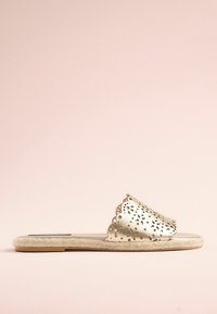 Metallic guld slide sandal med laserudskårne blomster mønstre, scalloped kanter og naturlig jute sål. Flad design, der er velegnet til afslappet brug.