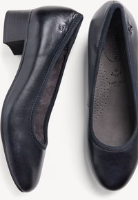 Tacchi in pelle blu scuro con una texture liscia, punta arrotondata e tacco a blocco. L'interno presenta una soletta imbottita con perforazioni per la traspirabilità.
