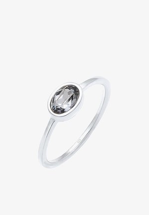 Bague en argent avec une pierre précieuse ovale, claire et facettée, sertie dans un chaton.