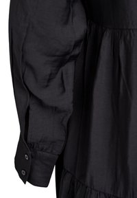 Must mustriga kleit, millel on kogutud seelik ja pikal varrukal nööpidega mansett. Sile tekstuur, millel on kerge sära.