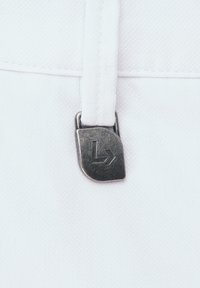 Biała tkanina z metalowym uchwytem zamka błyskawicznego z stylizowanym logo 'L'. Uchwyt zamka błyskawicznego jest prostokątny z gładkim wykończeniem.