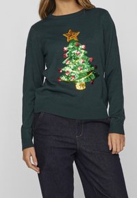 Mörkgrön tröja med ett paljettdesign av en julgran med en stjärna, färgglada julgransprydnader och en texturerad yta. Ribbad mudd och nederkant.