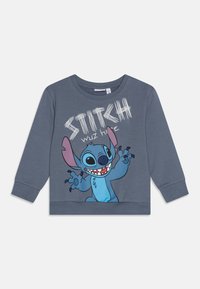 Sweatshirt en coton gris avec un personnage de dessin animé bleu, Stitch, aux grandes oreilles et un visage souriant, ainsi que du texte blanc : "STITCH ÉTAIT ICI."