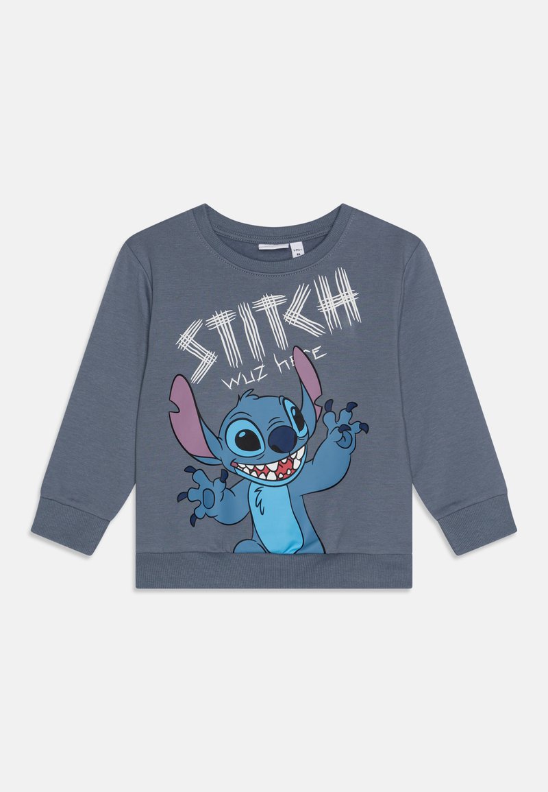 Sweatshirt en coton gris avec un personnage de dessin animé bleu, Stitch, aux grandes oreilles et un visage souriant, ainsi que du texte blanc : "STITCH ÉTAIT ICI."