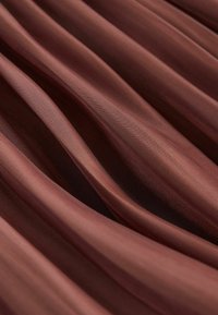 Tessuto marrone traslucido con una texture a coste, che mostra morbide pieghe e una leggera lucentezza. Il colore è caldo, creando un aspetto elegante.