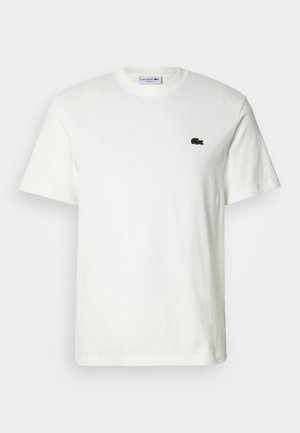 Wit katoenen T-shirt met een ronde hals en korte mouwen. Voorzien van een klein donkerbruin Lacoste-logo op de borst. Gladde textuur, casual pasvorm.