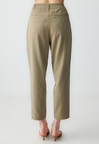 Chinos w kolorze khaki z prostą nogawką, wykonane z lekkiego materiału. Posiadają dwie tylne kieszenie oraz gładką fakturę.