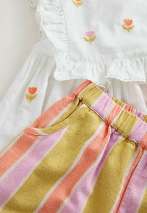 Rochie albă cu margini volanate și broderie florală, asortată cu pantaloni scurți cu dungi multicolore în nuanțe de roz, portocaliu și galben, având buzunare.