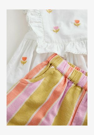 Valge kleit volangikujuliste äärte ja lilleõmblustega, koos mitmevärviliste triibuliste lühikeste pükstega roosa, oranži ja kollase toonides, millel on taskud.