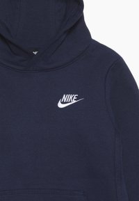 Felpa Nike blu navy con tasca a marsupio frontale, cappuccio con cordino e logo ricamato bianco sul petto. Materiale in cotone liscio.