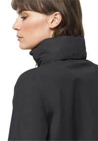 Veste noire imperméable avec un col haut. Texture lisse et design minimaliste, mettant en avant une silhouette ajustée.