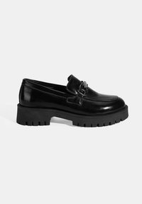 Zwarte leren loafers met een robuuste zool, voorzien van een decoratieve gesp aan de voorkant en een gladde, glanzende textuur.