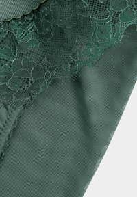 Dunkelgrüner Stoff mit feiner Netzstruktur und aufwendigen Spitzenverzierungen entlang des Randes.