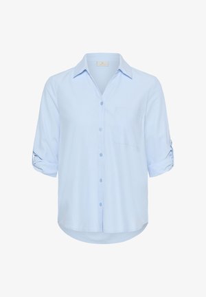 Chemise bleu clair à manches longues avec ouverture boutonnée sur le devant, manches retroussées maintenues par des lanières, et une poche poitrine.