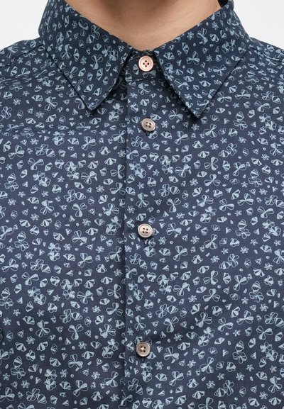 Μπλε ναυτικό πουκάμισο με κουμπιά και γιακά, με υφή υφάσματος και ανοιχτό μπλε ανθικό σχέδιο. Δύο ανοιχτό καφέ κουμπιά ορατά.