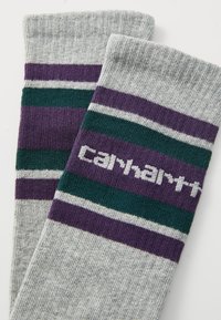 Gray socks featuring purple, green, and white stripes with the "Carhartt" logo in white. Knitted texture with ribbed cuff.