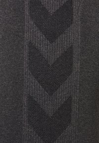 Pull en tissu gris foncé avec une texture côtelée et un motif en chevron noir au centre. Fini lisse avec un léger éclat.