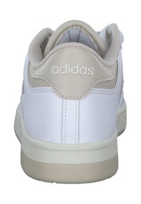 White sneaker with a smooth leather upper and beige accents. Features padded collar, textured rubber sole, and branded logo on the heel.