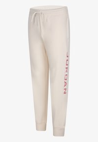 Cremfarbene Jogginghosen aus weichem Stoff, mit schmaler Passform, elastischem Bund und "JORDAN" in Pink entlang des linken Beins bedruckt.