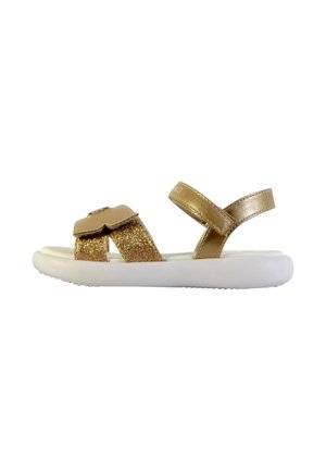 Sandalias planas doradas con tira de purpurina, correa ajustable en el tobillo, suela blanca lisa y diseño minimalista. Adecuadas para uso casual.