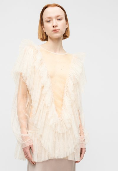 Διάφανη, μπεζ μπλούζα με στρωματοποιημένα βολάν κατά μήκος των μανικιών και της λαιμόκοψης, με βαθύ V-λαιμό. Μαλακό, υφασμάτινο ύφασμα με λαμπιρίσματα.