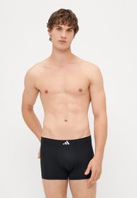 Boxer briefs atletas pretos com uma textura suave. Apresentam um logo branco na cintura e um design justo e ajustado.