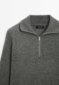 Grijze gebreide trui met een ritskraag, voorzien van ribgebreide accenten op de schouders en een soepele textuur in het lichaam. Etiket: Massimo Dutti.