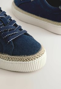 Marinblå denim sneakers med texturerad jute-detalj vid tån, gummisula och flätade snören med en kontrasterande rand.