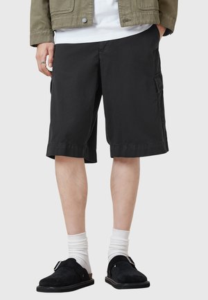 Black cargo shorts with a relaxed fit, made from durable fabric. Features side pockets and a simple hem design, paired with black clogs and white socks.