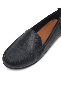 Czarne skórzane buty wsuwane z teksturowanym wykończeniem, okrągłym noskiem i dekoracyjnym przeszyciem wzdłuż krawędzi. Gładka podszycia.