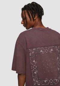 Overmaat, shirt met korte mouwen in bordeauxrood van katoen, met een ingewikkeld wit geborduurd ontwerp op de achterkant met bloemmotieven en patronen.