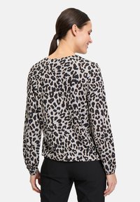 Leopardenmuster-Top in Beige und Schwarz, mit langen Ärmeln, rundem Ausschnitt und lässiger Passform. Glattes Material mit verspielten Musterdetails.
