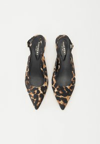 Los tacones de tirante con estampado de leopardo presentan un diseño de punta afilada con un interior negro suave y una correa ajustable. Están hechos de tela.