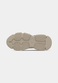 Semelle de basket beige clair avec des motifs de bande de roulement rectangulaires segmentés et des rainures courbes sur un fond clair uni.