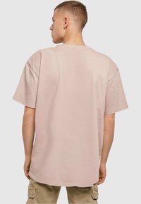 Oversized kortærmet T-shirt i blødt pastelpink stof med rund hals og let buet kant for en afslappet pasform.
