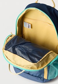 Μπλε και κίτρινο σακίδιο με φερμουάρ, τσέπη από δίχτυ και εσωτερικά διαμερίσματα· διαθέτει υφασμάτινη υφή και φερμουάρ σε αντιθετικά χρώματα.