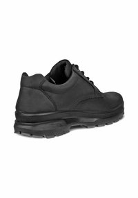 Zapato de cuero negro con punta redondeada, parte superior texturizada y suela de goma con patrones de agarre y cordones para un ajuste seguro.