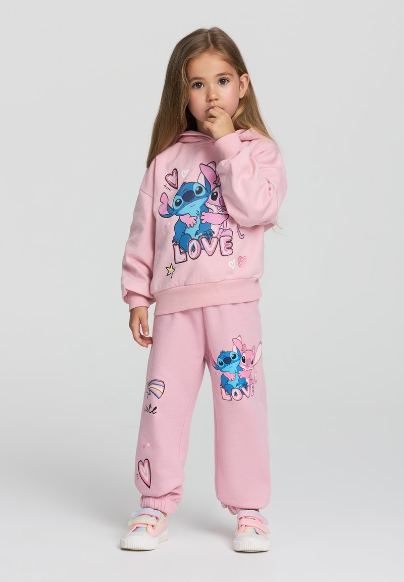 Felpa e pantaloni rosa chiaro con personaggi dei cartoni animati e testo "LOVE", polsini elastici e accenti colorati. Materiale in misto cotone.