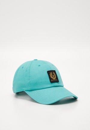 Turquoise baseballpet met een gebogen klep en een zwart label met een gouden embleem en het woord "Belstaff" aan de voorkant.