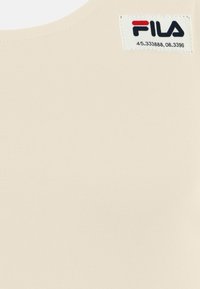 FILA beige tanktop, gemaakt van gladde, elastische stof. Heeft een ronde halslijn en een label met cijfers en logo aan de bovenlinkerzijde.