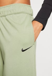 Ljusgröna Nike sweatpants med strukturerad yta, med en elastisk midja och en svart logotyp på vänster ficka.