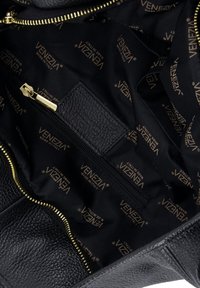 Innenraum einer schwarzen Ledertasche mit goldfarbenem Reißverschluss, gefüttertem Stoff mit Markenlogo und einer kleinen Reißverschlusstasche mit der Aufschrift "Venezia Made in Italy".