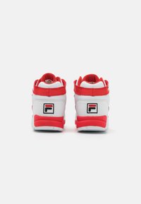 White and red high-top sneakers with padded collar, logo detail on heel, textured rubber sole, and contrasting stitching.