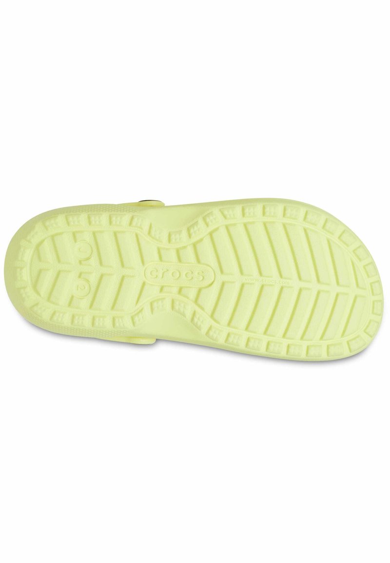 Suela de goma de color amarillo claro con un dibujo en la banda de rodadura para mayor agarre, con la marca "Crocs" grabada en el centro. Textura suave en toda la superficie.