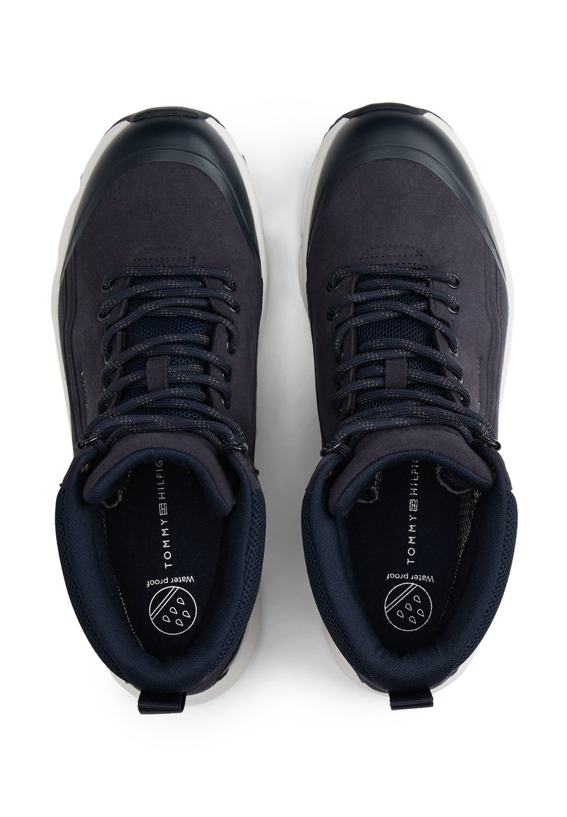 Navy blue waterproof shoes with a suede and mesh upper, rubber toe cap, and flat laces. Features a patterned insole and branded interior.