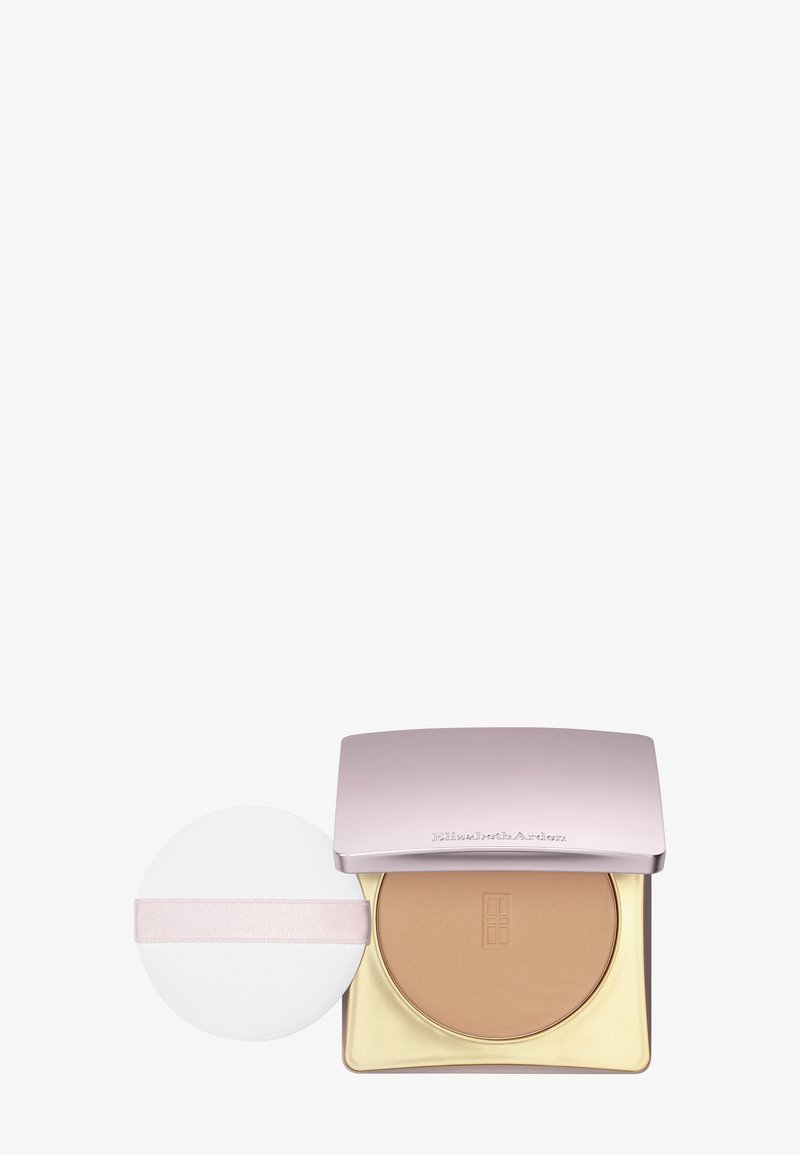 Kompaktowy puder w różowym metalicznym etui ze złotą podstawą; zawiera okrągłą białą gąbeczkę z jasnoróżową opaską. Gładka tekstura, jasnobrązowy odcień.