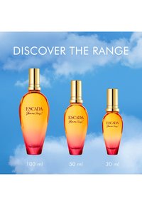 Drie Escada "Yum me, Sunny!" parfumflessen in 100 ml, 50 ml en 30 ml met gouden doppen tegen een achtergrond van een blauwe lucht.