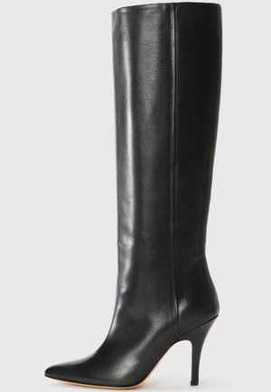 Botte noire en cuir, montant jusqu'au genou, avec un bout pointu et un talon aiguille. Texture lisse et design épuré avec des embellissements minimes.