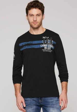 Camiseta de manga larga negra con rayas azules y gráficas blancas. Presenta un cuello redondo y mangas ajustadas, confeccionada con un tejido suave.