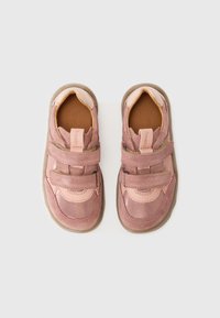 Chaussures en cuir rose avec deux sangles Velcro, textures lisse et suédée, bout arrondi et une semelle en caoutchouc robuste.